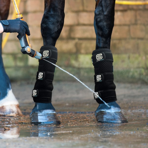 Horse being washed with a hose, wearing black EQU StreamZ Coolboots on legs.
